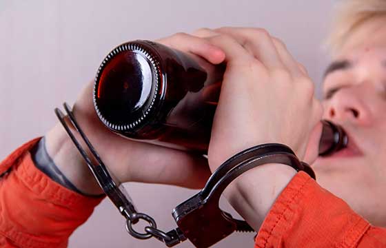  Подростковый алкоголизм: подросток в наручниках пьет пиво из бутылки